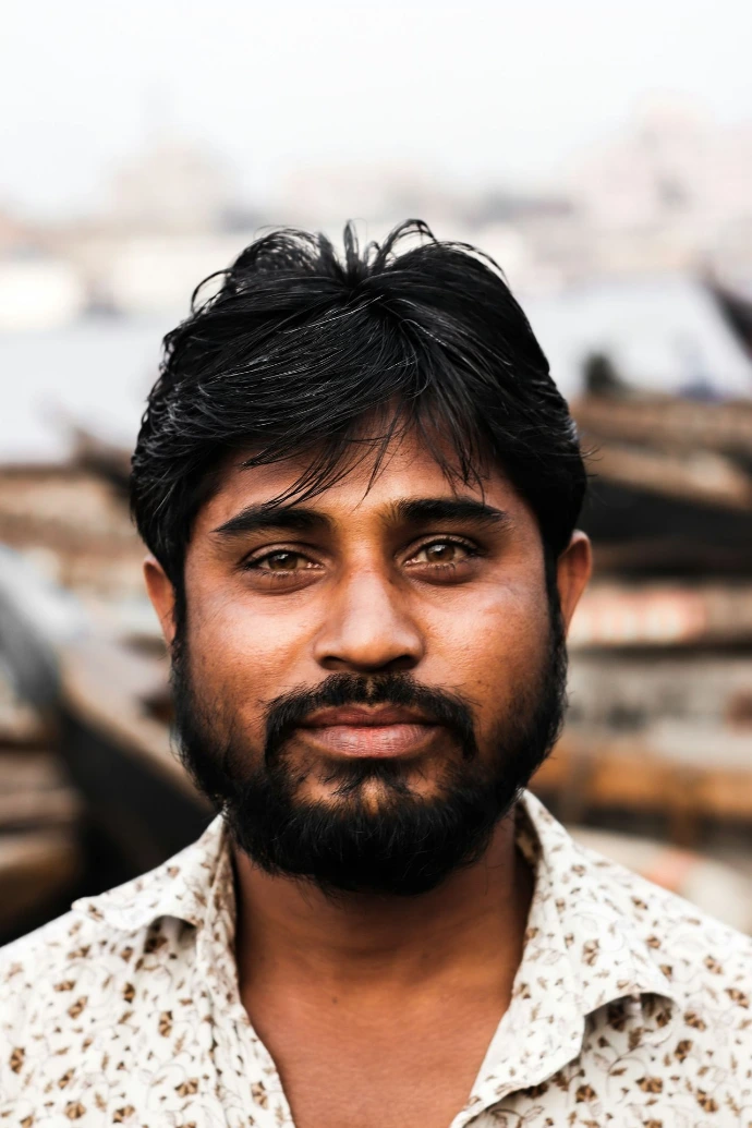 a man with a beard standing in front of boats